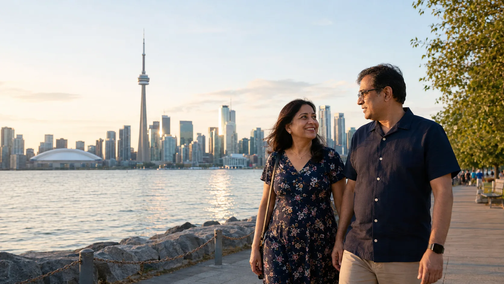 Couple walking beside Toronto waterfront with the skyline behind them